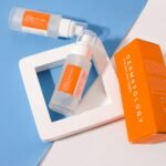 Stylish presentation of dermatology skincare products with orange packaging on a geometric background.